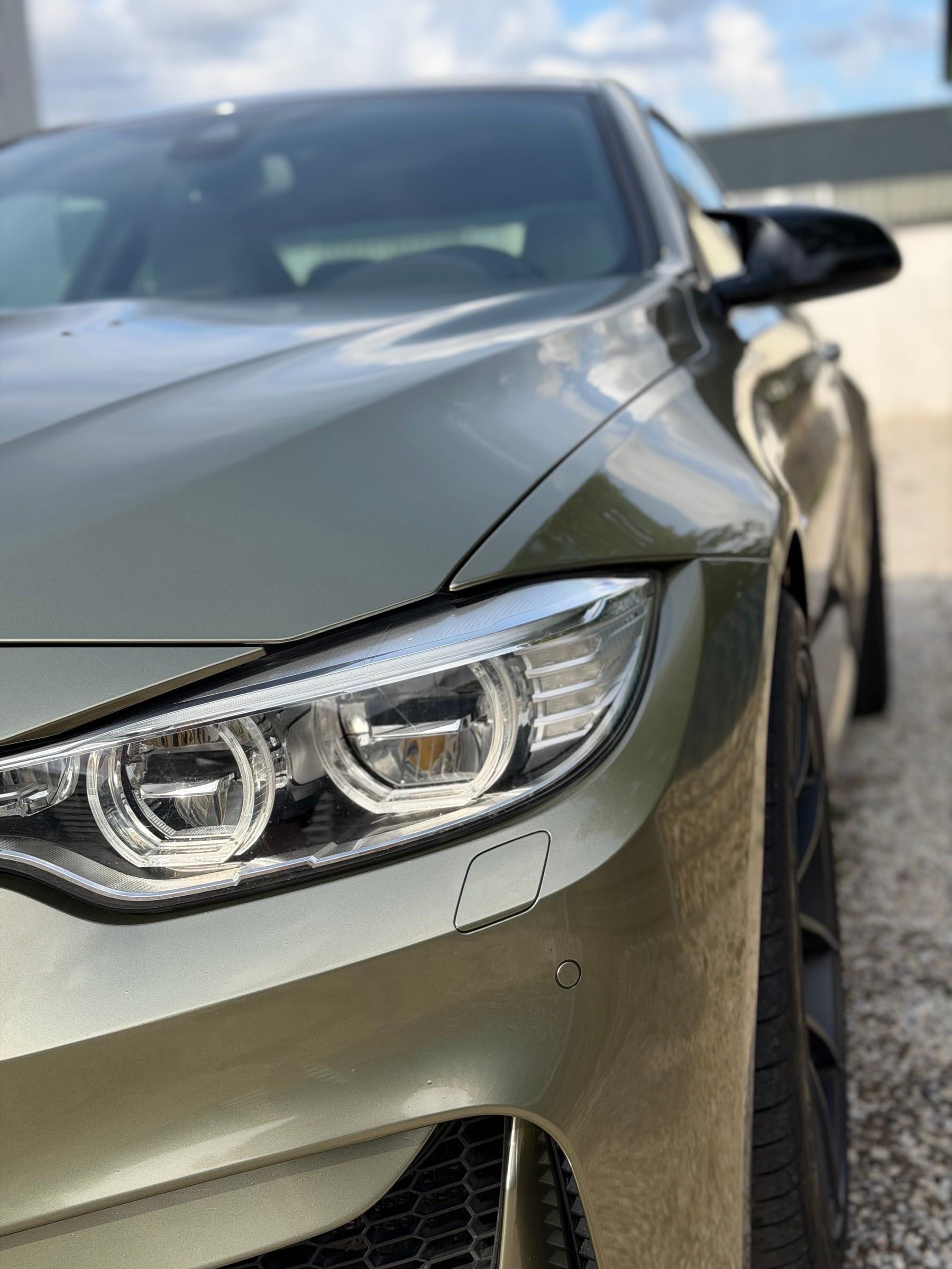 Detailaufnahme: Front eines olivgrün folierten BMW M4 mit Scheinwerfer und Motorhaube – Handwerk von STUDIO ONE