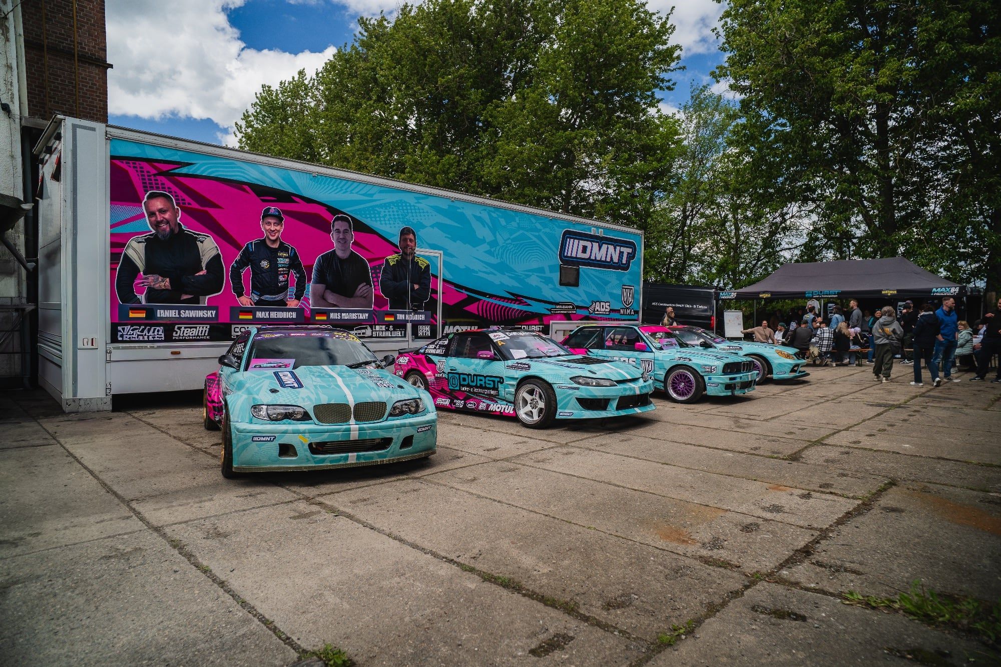 DMNT-Teamtruck und Rennfahrzeuge mit einheitlicher Livery und Fahrzeugbeschriftung von STUDIO ONE