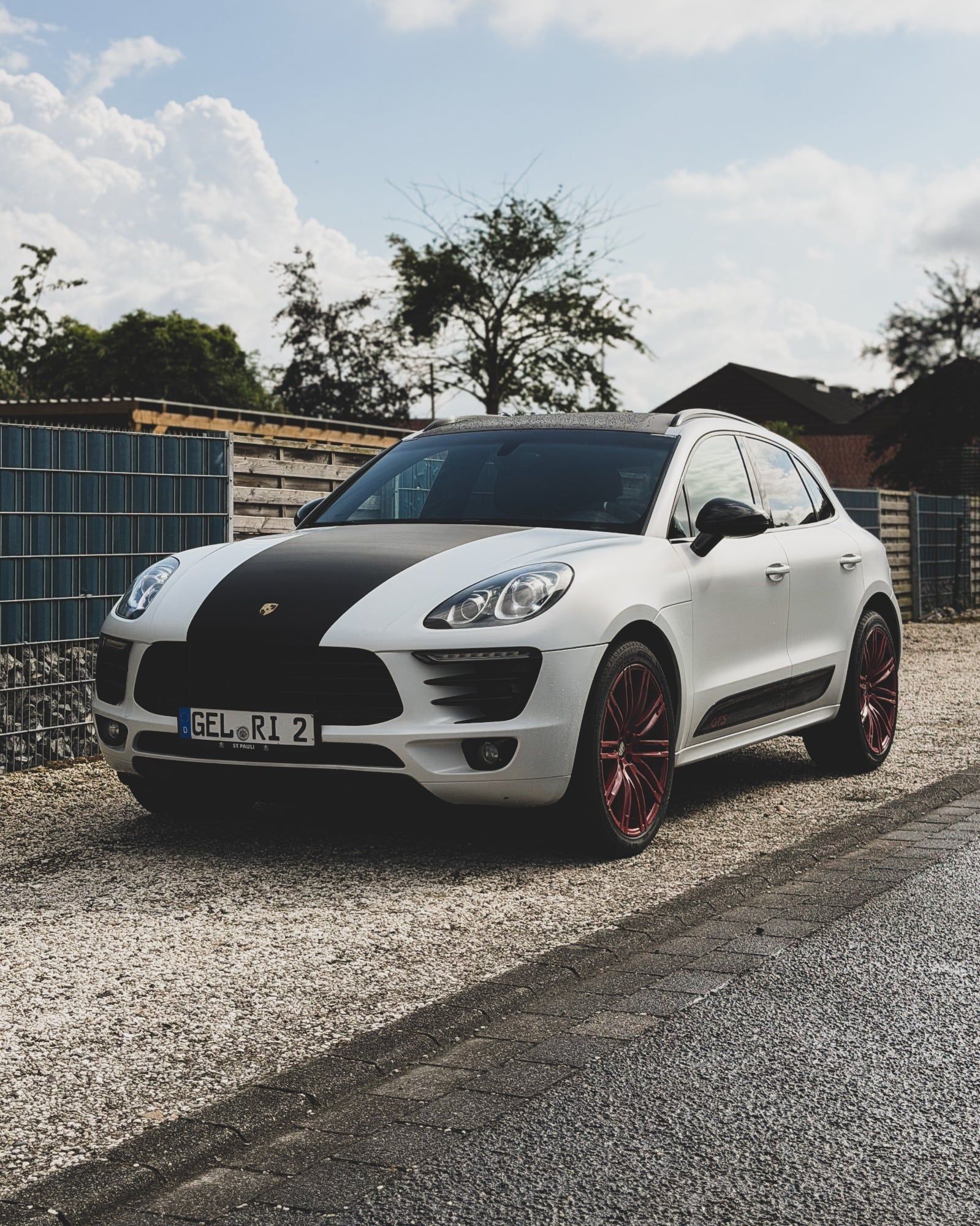 Weißer Porsche Macan mit Carbon-Streifen auf der Motorhaube und roten Felgen, foliert von STUDIO ONE